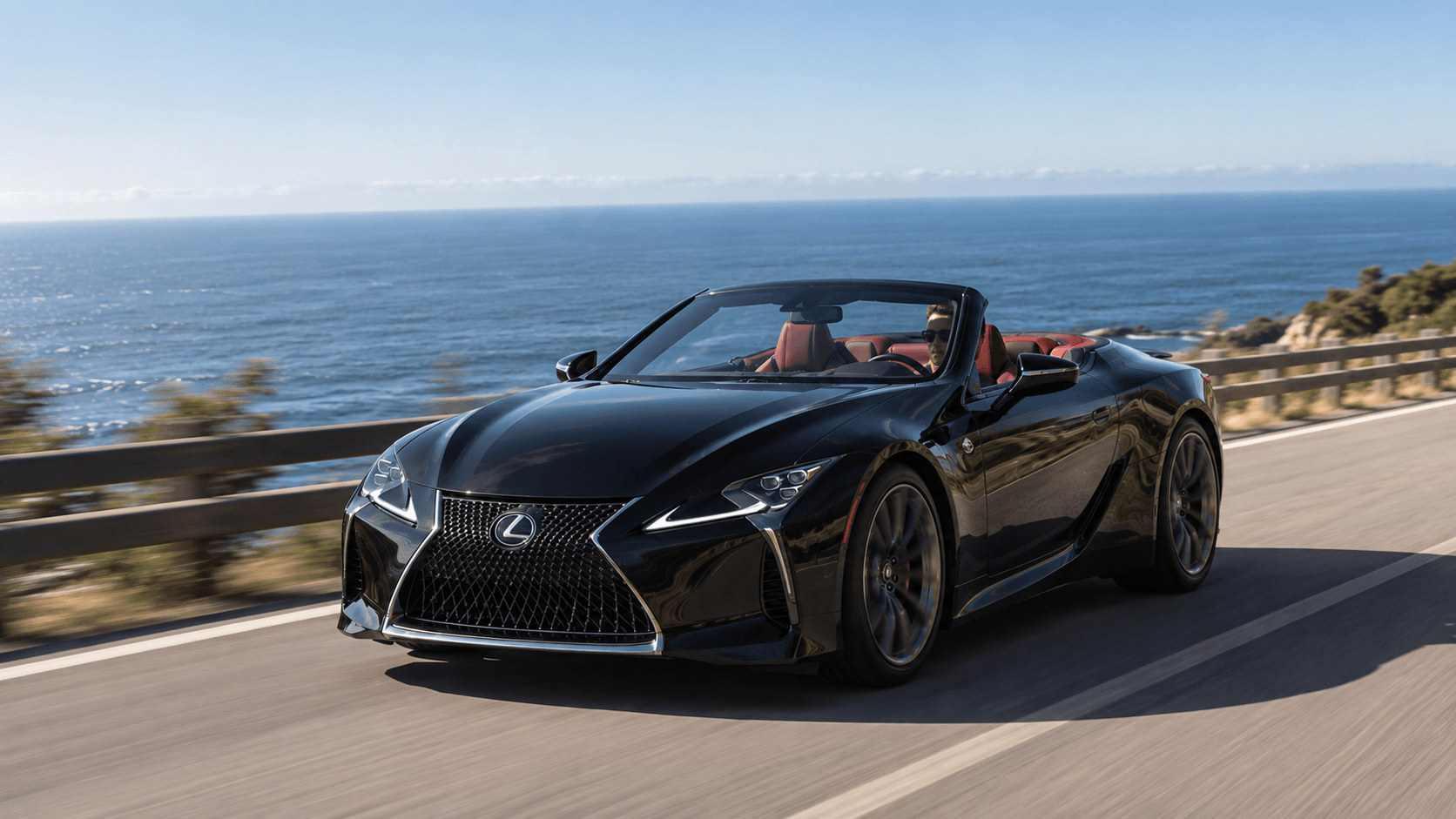 Black convertible driving along a coastal road